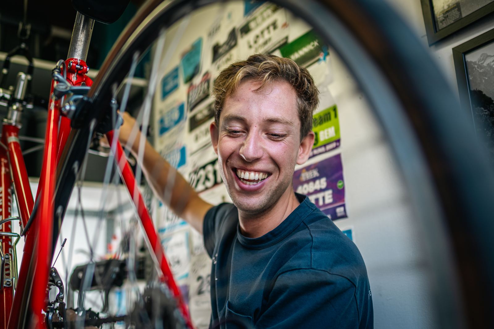 Yannick lachend in de werkplaats, met startnummers aan de muur