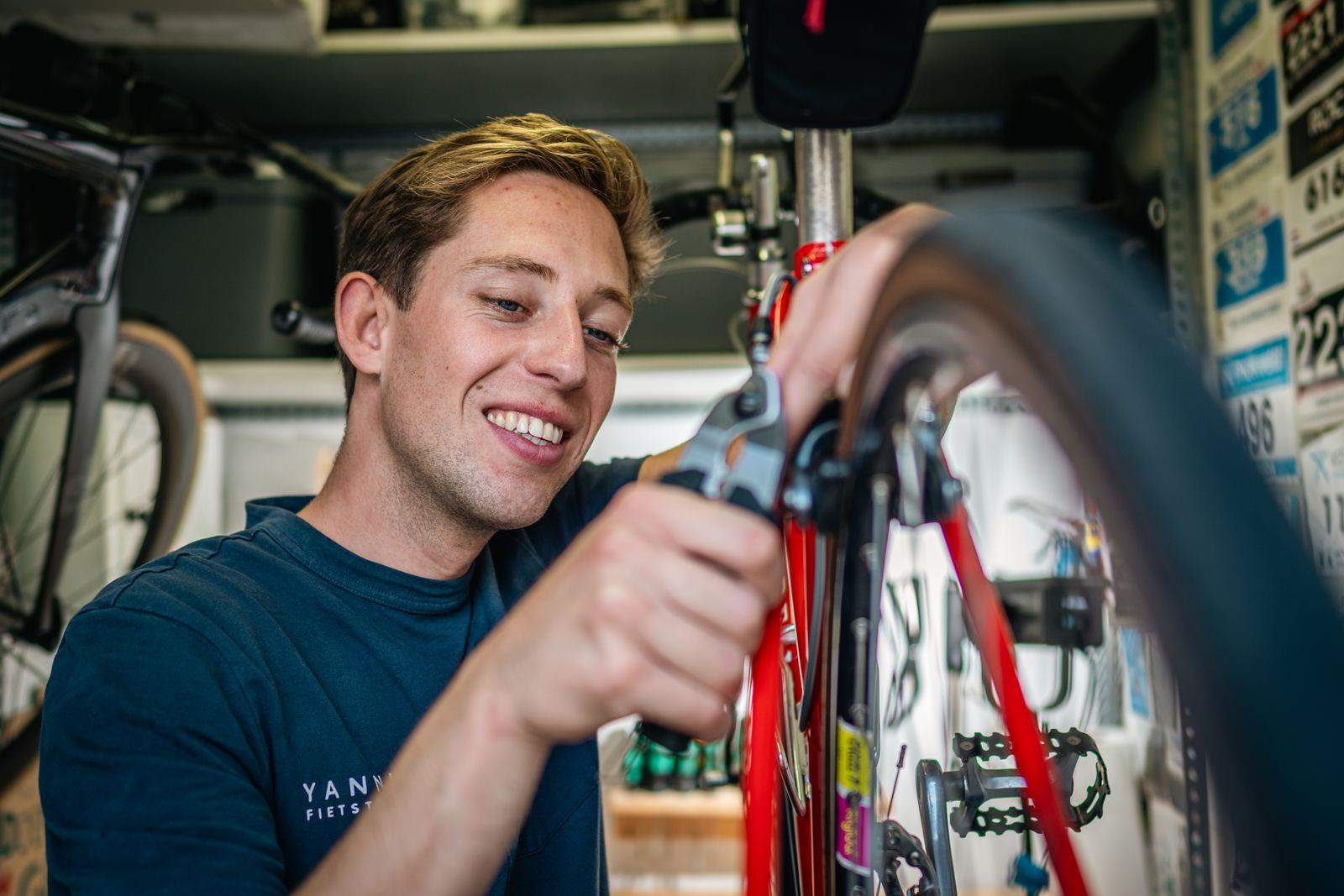 Yannick aan het werk aan een rode racefiets in de werkplaats